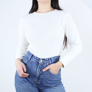 May include: A white waffle knit long-sleeve shirt with a crew neck.