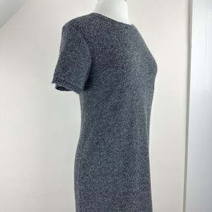 May include: A gray short-sleeved dress made of a textured fabric. The dress has a round neckline and a fitted silhouette.