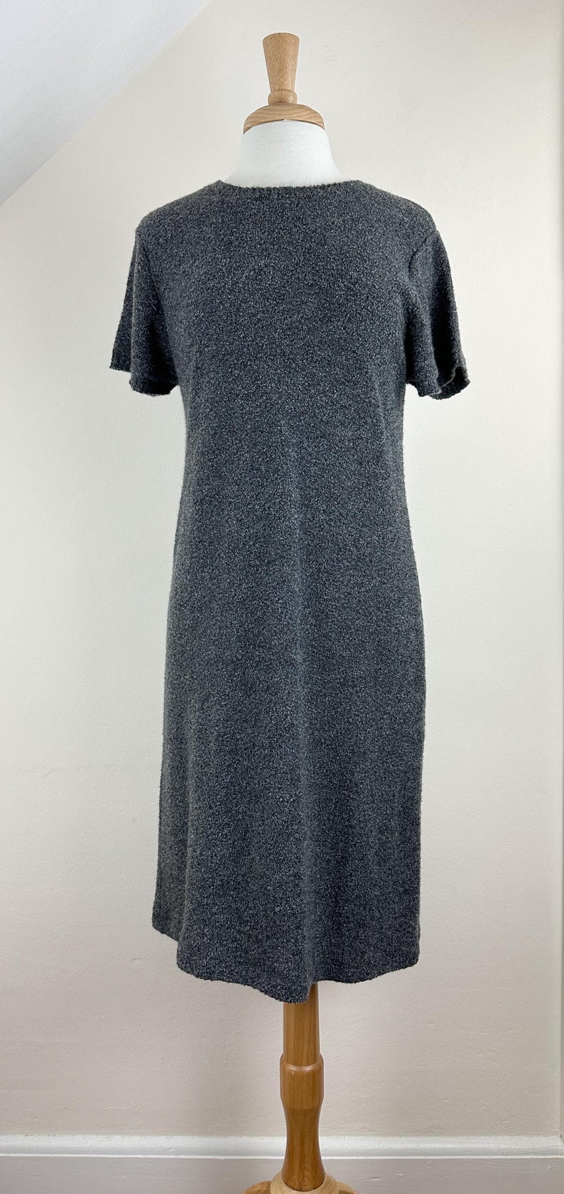 May include: A gray short-sleeved knit dress on a mannequin.