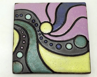 May include: A square ceramic tile with an abstract design. The tile features a swirling pattern of purple, yellow, green, and blue colors with black outlines. The tile has a textured surface.