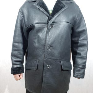 Men&#39;s black sheepskin coat with buttons. Stylish men&#39;s sheepskin coat with black fur.