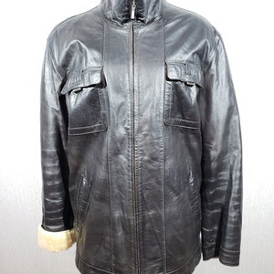 Men&#39;s sheepskin coat in black color with a metal zipper. Men&#39;s sheepskin coat is black on beige sheepskin.