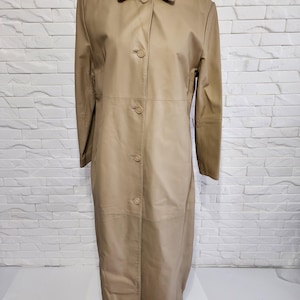 Blouson en cuir fiable pour femme. Manteau en cuir simple beige. Veste longue en cuir avec boutons en plastique.