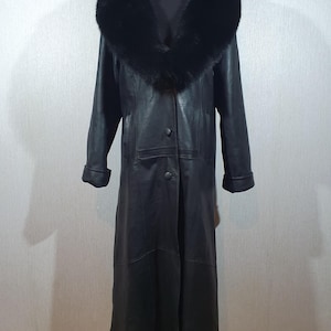 Imperméable long et élégant en cuir pour femmes. Manteau noir en cuir véritable avec col en fourrure.