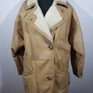 Wonderful women&#39;s warm sheepskin coat made of genuine pleasant sheep fur. Stylish brown sheepskin coat with buttons.