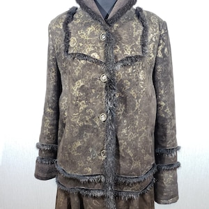 Delightful women&#39;s warm sheepskin coat made of genuine warm brown fur. Stylish brown sheepskin coat with luxurious ornamentation.
