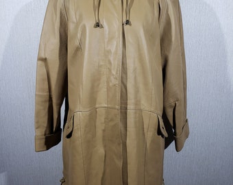 May include: Tan leather coat with a high collar and button closure. The coat features a drawstring hood, pockets, and decorative ties at the hem. The sleeves are cuffed. The coat is displayed on a mannequin.
