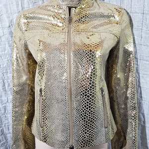 Une superbe veste en cuir pour femme avec une fermeture éclair en plastique. Veste en cuir pour femme de couleur dorée, avec décoration en peau de serpent.