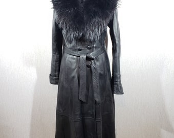 Stylish long women's leather raincoat. Black coat made of genuine leather with a fur collar.