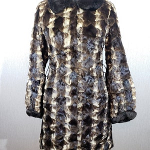A luxurious women&#39;s fur coat with a hood decorated with beads. Warm brown women&#39;s fur coat made of genune fur.