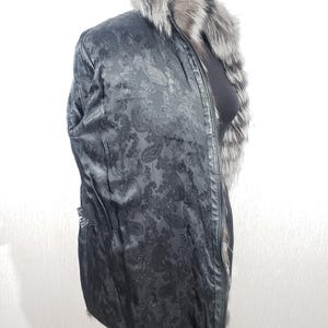 K&ouml;nnte beinhalten: Schwarze Jacke mit Paisley-Musterfutter und Pelzkragen. Die Jacke hat einen Rei&szlig;verschluss und eine schwarze Au&szlig;enseite. Der Pelzkragen ist grau und wei&szlig;. Die Jacke ist mittellang.