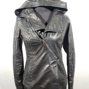 Charmante veste en cuir pour femme avec fermeture éclair en métal. Blouson en cuir gris mystérieux pour femme à capuche.