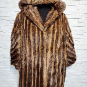 Women&#39;s fur coat made of genuine warm fur. Warm brown women&#39;s fur coat with hood.