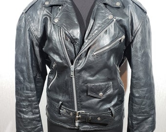 May include: Black leather jacket in a classic biker style. It has a notched collar, an asymmetrical zip, multiple zipped pockets, and a waist belt. The jacket is displayed on a black mannequin.