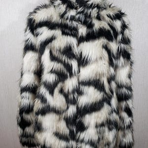 Beautiful black and white faux fur coat for women. Stylish fluffy women&#39;s coat.