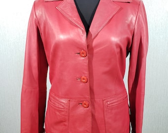 May include: A red leather blazer with a classic design. The jacket features a notched collar, three-button closure, and two front pockets. The sleeves have folded cuffs. The blazer is displayed on a black mannequin.