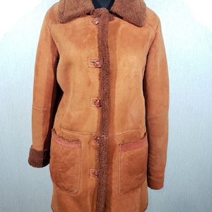 Wonderful women&#39;s warm sheepskin coat made of genuine pleasant sheep fur. Stylish brown sheepskin coat with buttons.
