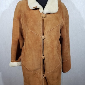 Wonderful women&#39;s warm sheepskin coat made of genuine pleasant sheep fur. Stylish brown sheepskin coat with buttons.