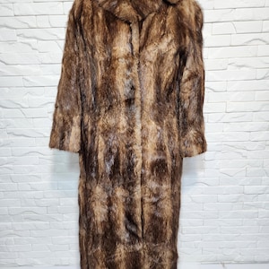 Women&#39;s long fur coat made of genuine warm fur. Warm brown women&#39;s fur coat with genuine fur.