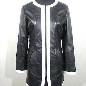 Graceful women&#39;s jacket of black color made of genuine leather. Black jacket with white leather trim.