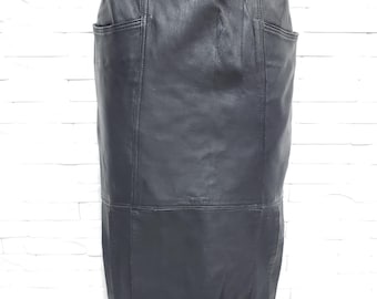May include: A black leather skirt with a knee-length hemline. The skirt has two front pockets and vertical seams for a tailored look. The skirt is displayed on a mannequin.