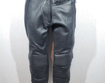 May include: Black leather motorcycle pants with reinforced knee panels and a zippered pocket. The pants have a button and zipper closure at the waist and a white logo on the waistband.
