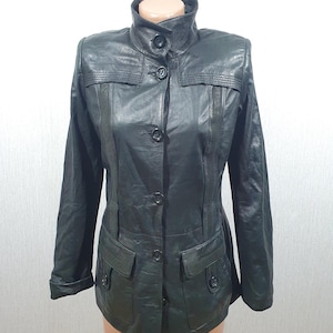 Süße schwarze Damenlederjacke. Damen schwarze Lederjacke mit Knöpfen und Gürtel.