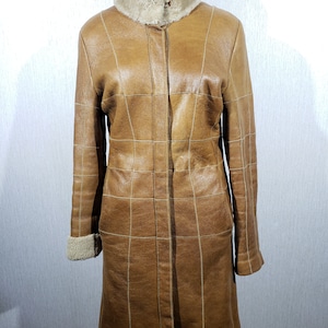 Wonderful women&#39;s warm sheepskin coat made of genuine fur. Stylish brown women&#39;s sheepskin coat with metal buttons.