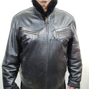 Men&#39;s sheepskin coat in black with a metal zipper. Sheepskin coat for men on a black sheepskin and with a beaver collar.