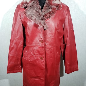 Stylish red women&#39;s leather raincoat. Cute women&#39;s leather jacket with a fur collar.