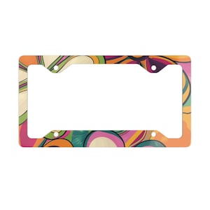 May include: License plate frame with a colorful, retro design. The frame features a vibrant pattern of swirling shapes in orange, pink, green, and yellow. The frame has four mounting holes and a rectangular opening for the license plate.