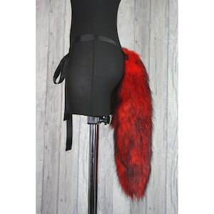 May include: A red and black faux fur tail with a black satin ribbon attached to a black belt.