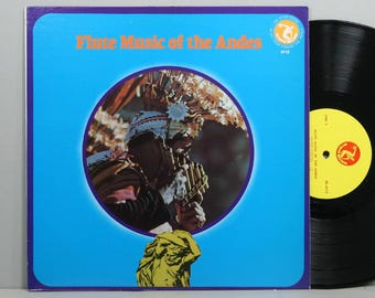May include: Vintage vinyl record album titled "Flute Music of the Andes." The album cover features a person playing a flute, set against a blue background. The record itself is black with a yellow label.