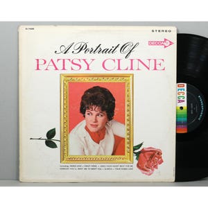 May include: A vinyl record album titled A Portrait Of Patsy Cline on the Decca label. The cover features a portrait of Patsy Cline in a gold frame, surrounded by a red rose, with the tracklist including Faded Love and Crazy Arms below.