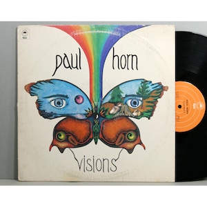 May include: A vintage vinyl record album cover featuring a colorful butterfly with eyes and a rainbow. The album is titled "Paul Horn Visions".
