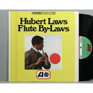 May include: A vintage vinyl record album cover for "Hubert Laws Flute By-Laws." The cover is yellow with black text and features a photo of a man playing a flute. The Atlantic Records logo is at the bottom.