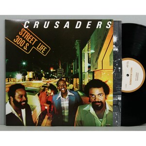May include: A vinyl record album cover featuring a group called "Crusaders" with the album title "Street Life 300 S.". The cover art shows a nighttime city street scene with three men in the foreground.