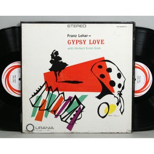 May include: A vintage vinyl record album cover with a white background and colorful abstract art. The album is titled "Gypsy Love" by Franz Lehar, featuring Herbert Ernst Groh. The cover features a red, white, and black abstract design with a woman in a black dress dancing.
