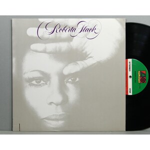 May include: Album cover for Roberta Flack's album. The cover features a grayscale image of a woman's face with a hand partially covering her eyes. The album title is in a cursive font. A vinyl record is visible on the right.