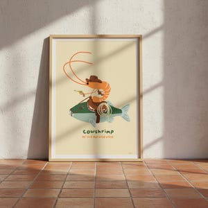 Peut inclure: Impression d'art encadrée avec une illustration d'une crevette cowboy sur un poisson. La crevette porte un chapeau de cowboy marron et tient un pistolet. Le texte "Cowshrimp of the old wild west" est en bas.