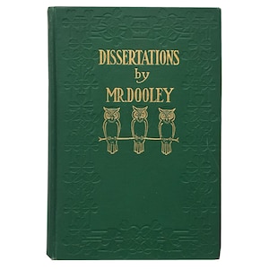 Op de afbeelding: Een groen boek met een gouden reliëfpatroon en de titel "DISSERTATIONS by MR. DOOLEY" op de voorkant. Drie gouden uilen zitten op een tak boven de titel.
