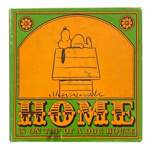 May include: A green and orange illustration of a dog house with a dog lying on top of it. The text "HOME IS ON TOP OF A DOG HOUSE" is below the image.