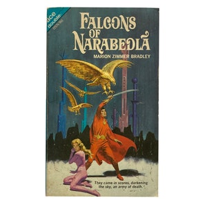 Może przedstawiać: Okładka książki z fantastyczną ilustracją mężczyzny w czerwonym płaszczu trzymającego miecz, kobiety w różowym garniturze i trzech złotych sokołów latających w powietrzu. Tytuł książki to "Falcons of Narabedla" autorstwa Marion Zimmer Bradley. Tekst na dole okładki brzmi: "Przybyli w zastępach, zaciemniając niebo, armia śmierci."