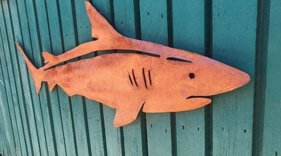 Rusty Shark wall art. Made out of 18 gauge steel. Has sawtooth Hanger welded on the back. Had a rust patina for a rustic look.