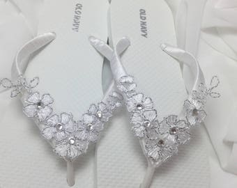 May include: A pair of white flip-flops with silver floral embellishments. The flip-flops are labeled "Old Navy" on the straps.