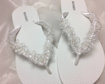 May include: Pair of white flip flops with a white lace trim and the words "Old Navy" printed on the straps.