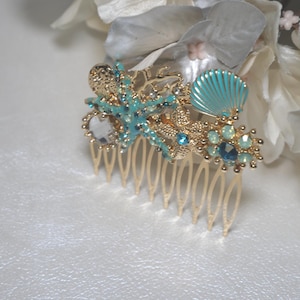 May include: Gold hair comb with blue and clear rhinestones, a blue seashell, and two starfish.