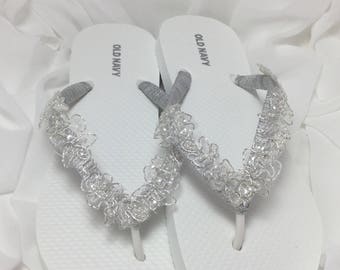 May include: White flip flops with silver lace trim and the words "Old Navy" printed on the straps.