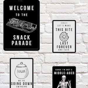 May include: Four black and white signs with humorous text and illustrations. One sign says "Welcome to the Snack Parade" with a snack tray graphic. Another says "Honest, Let's Make This Bite Last Forever and Ever" with a donut. The other two signs say "Sugar, We're Going Down Swinging" and "Cause I'm Just a Middle-Aged Dirtbag Baby".