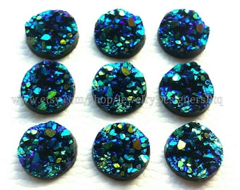 Op de afbeelding: Tien ronde, iriserende blauwe en groene cabochons met een glinsterende, kristal-achtige textuur. Deze cabochons zijn perfect voor het maken van sieraden.